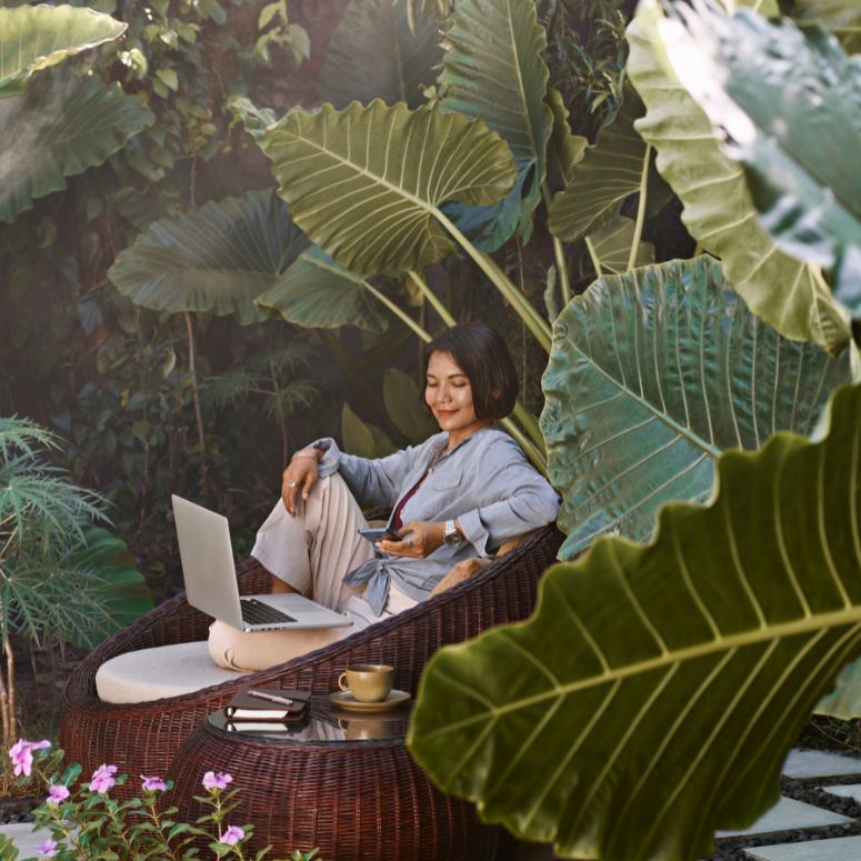 woman working remotely outdoors in a tropical setting