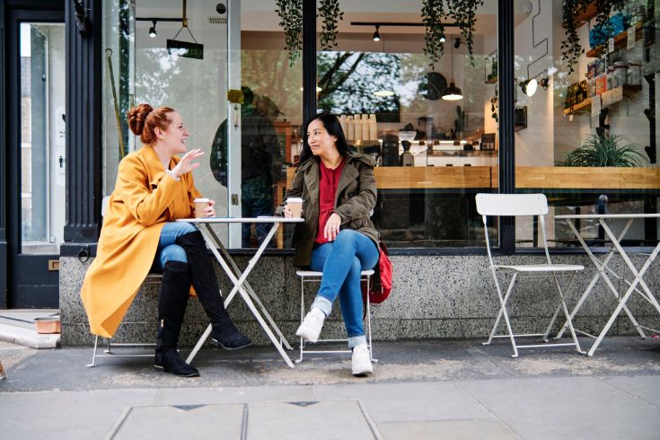 Two friends having coffee outside in one of Toronto's best neighbourhoods