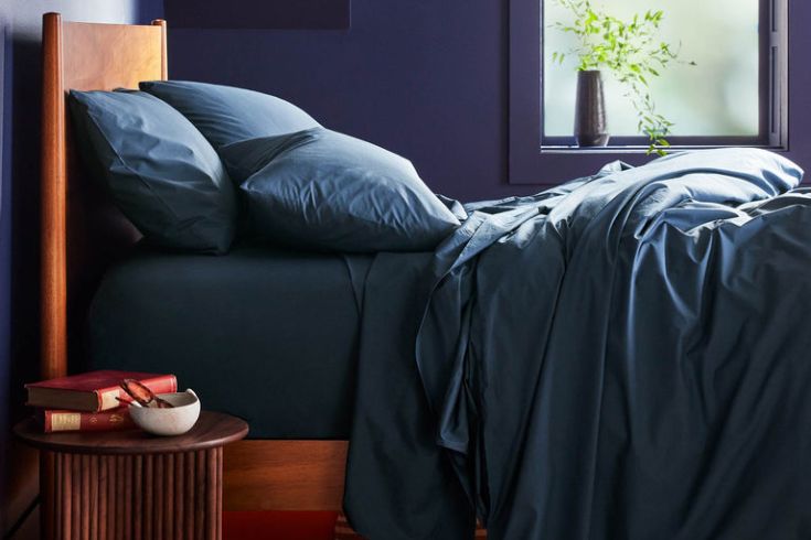 Blue sheets, wooden bed in a blue bedroom. 