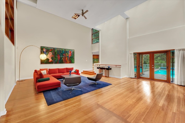 White living room with wooden floors and lookout to pool