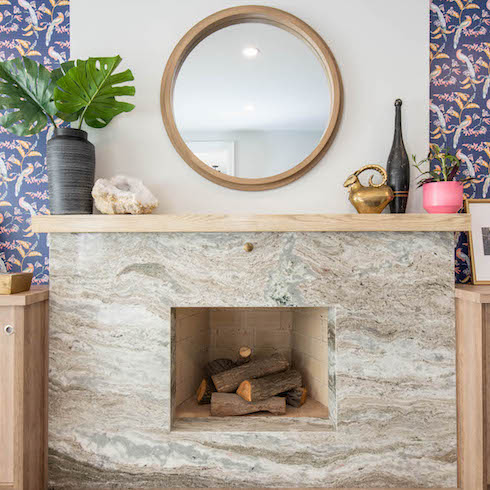 Stone façade fireplace updates and streamlines the look of this living making it feel modern and fresh with patterned wallpaper and built-in storage units as featured on Home Network