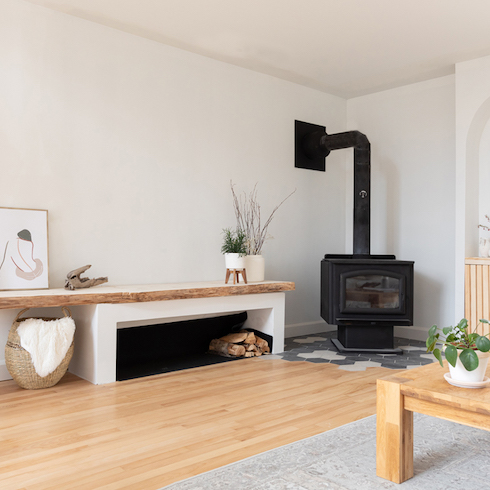 White living room with black fireplace and asymmetrical wood storage area