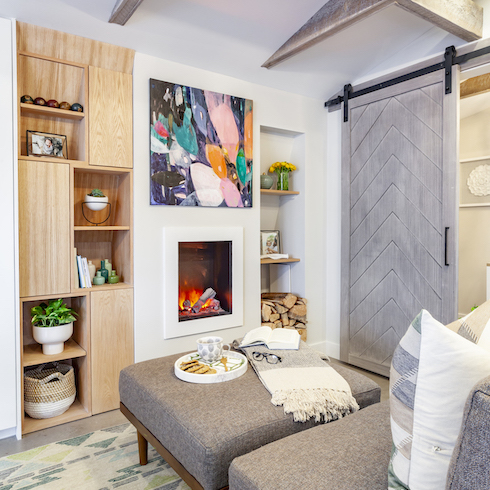 Chic Scandinavian inspired interior with grey sectional couch, electric fireplace and green patterned rug