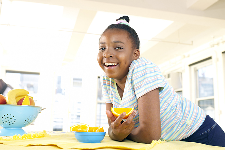 Girl (9-11) in kitchen with orange section, portrait