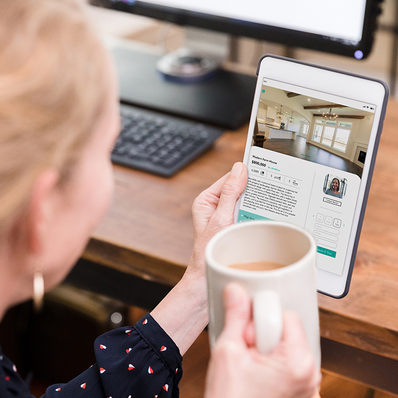An adult businesswoman looks at the interior of a home while using a mobile app on her digital tablet.