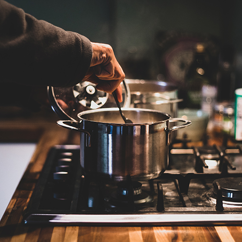 A man cooking at night, stirring the stew pan. People who eat home-cooked meals on a regular basis tend to be happier and healthier.