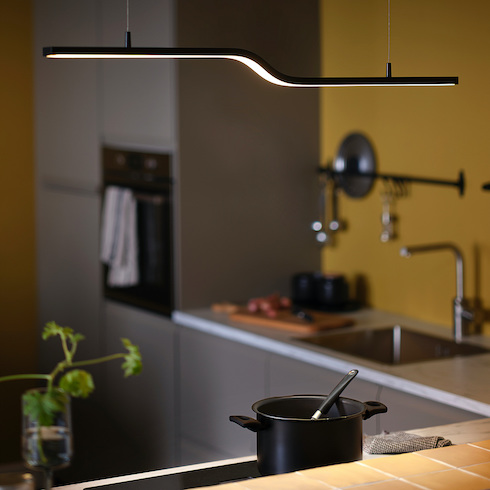 Pilskott LED Pendant Lamp from Ikea Canada featured in Home Network’s kitchen lights gallery hanging above a small modern kitchen with yellow walls, grey cabinets, black pot and spoon on a stove top with a kitchen sink and chopping board in the background