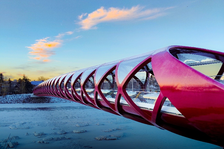 Calgary, Alberta's Peace Bridge over a snowy landscape and a blue sky overhead.