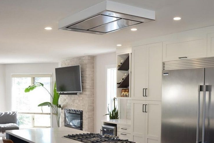 A clean modern kitchen with a sleek brushed metallic flat mount range kitchen hood