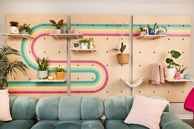 A living room with DIY shelves behind the couch with plants of them