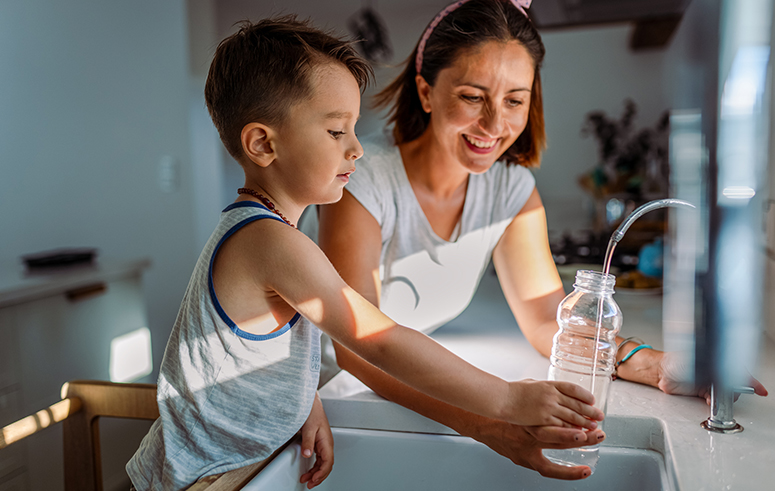Mother and her toddler filling a glass with filtered water right from the tap