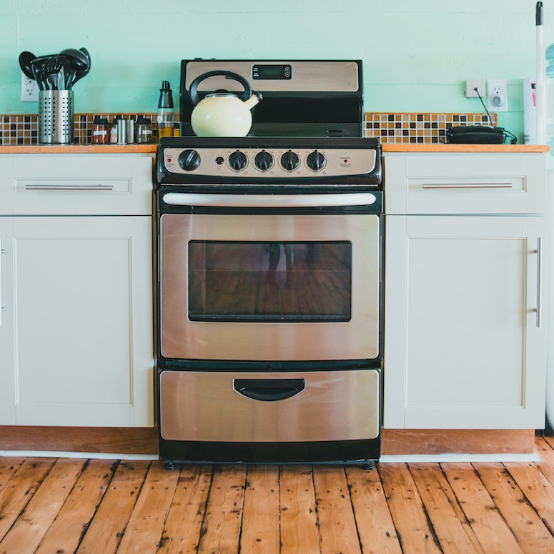 Stainless steel stove with wood floors and teal painted wall