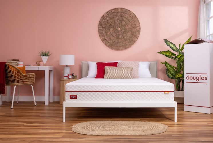 Bed in a pink room with woven art