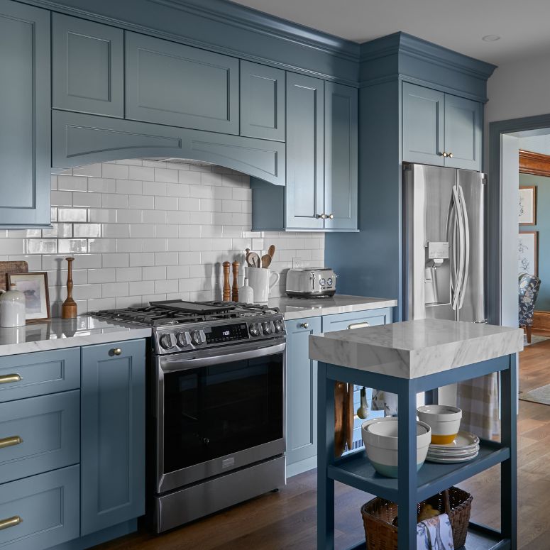 Blue kitchen cabinets with white subway tile backsplash and stainless steel appliances