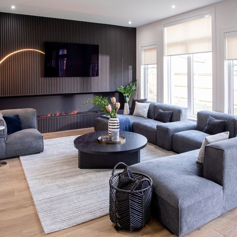 Living room with big bright windows and dark gray panelling and furniture