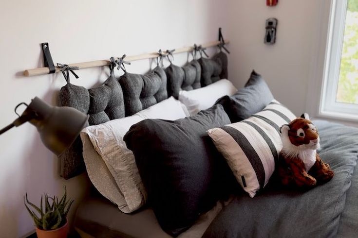 More Sustainable Holidays featuring a DIY Headboard by Courtney Ryall made with chair cushions and a stack of grey and beige pillows and a stuffed toy tiger
