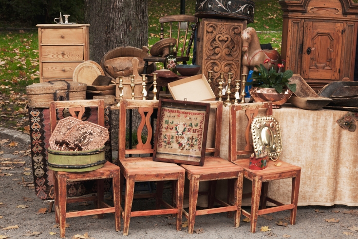 Stand at an outdoor market with antique wooden furniture. 