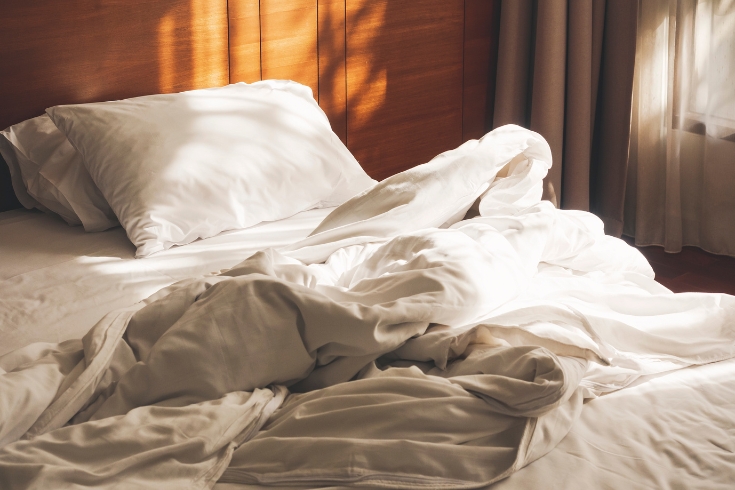 Bed covered with white cotton looking sheets and cover
