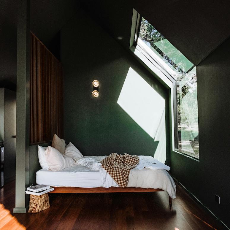 White bed in a green bedroom with a large skylight and wood floors for Home Network When You Should Replace Your Mattress