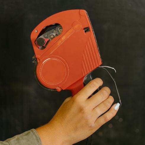 Red labeller held by a female hand against a black background