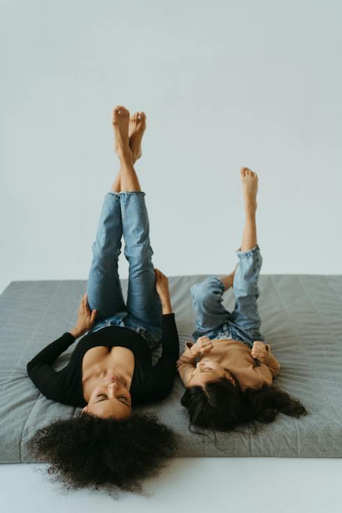 A woman and child stick their feet in the air while lying on a mattress for Home Network When You Should Replace Your Mattress
