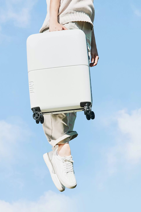 for Home Network Best Carry-On Luggage held by a person jumping up into a blue sky for Home Network Best Carry-On Luggage
