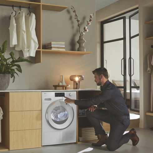 A male loading his sustainable Miele dryer, a home appliance trend for 2025