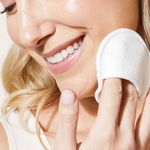 Woman cleaning face with reusable round