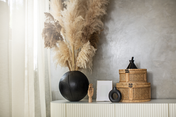 Styled Japandi design decoration objects - rattan basket, wooden vase on fluted wooden door sideboard.