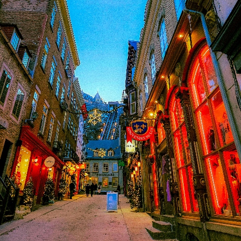 A street in Old Québec City during the winter with colourful lights in shop windows.