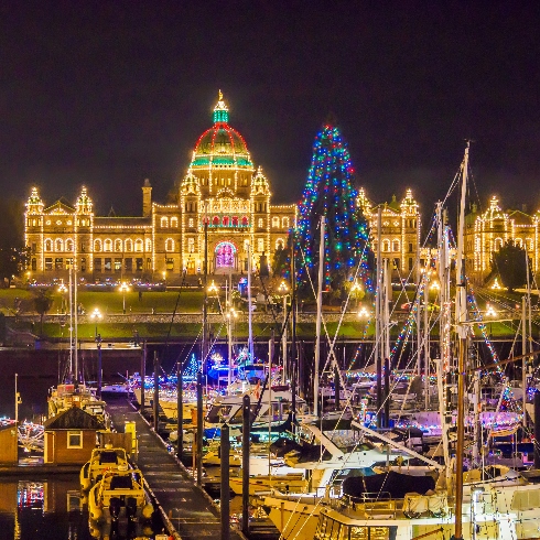 Victoria, British Columbia during the Christmas season with the buildings and boats decorated with colourful lights.