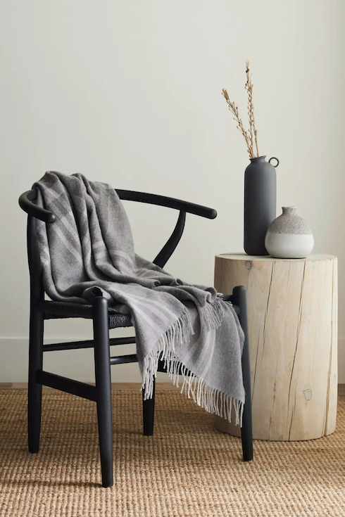Silk & Snow alpaca throw on a wooden chair next to a stump side table as part of Home Network Last Minute Gifts