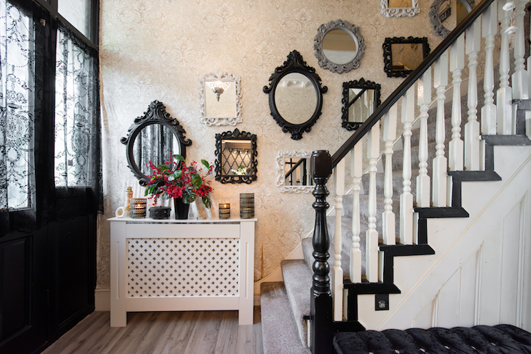 A general interior view of a hallway with staircase and multiple various antique mirrors