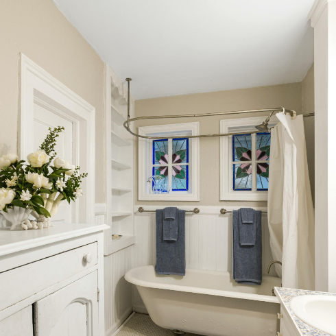 A white bathroom with a clawfoot tub and white shower curtain