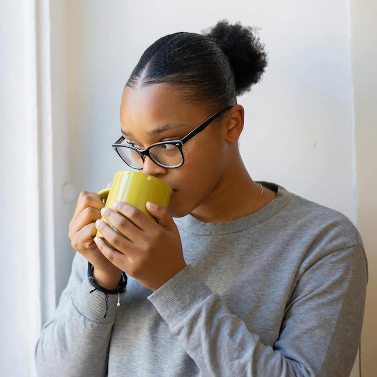 Woman sipping from a coffee cup and staring out the window