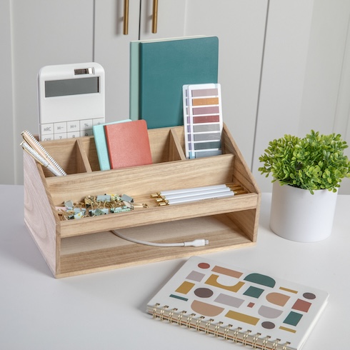 Assorted pens and desktop items are organized in a wood desktop organizer.