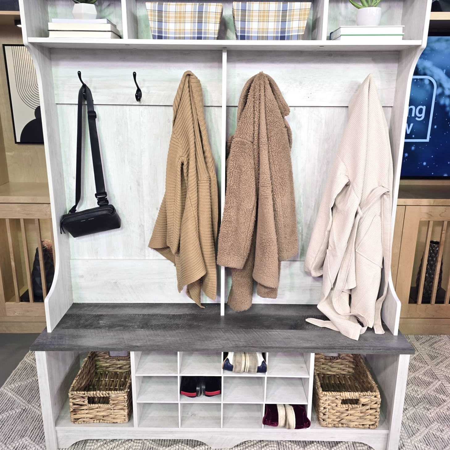 Coats and a purse hang from hooks, while shoes sit in organization slots, on a hall storage unit and bench.