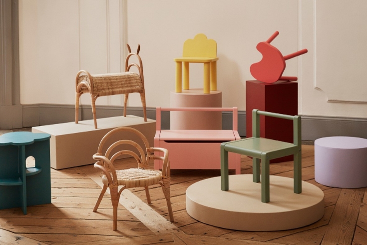 Children's rattan furniture collection by H&M Home set including yellow, green and red chairs and a pink storage bench.