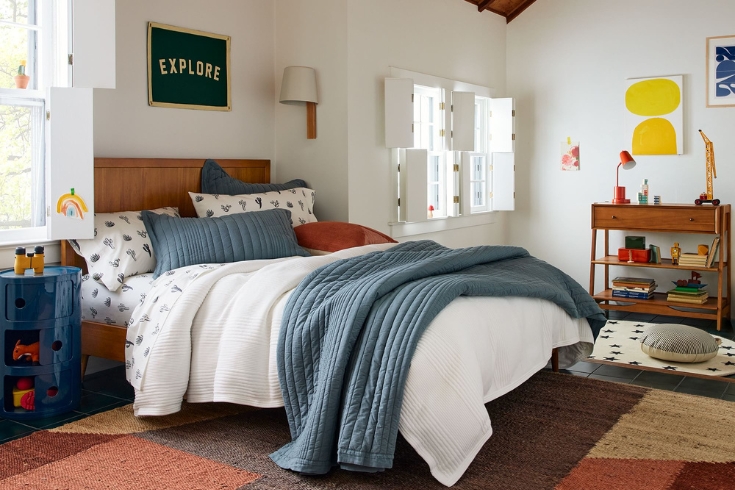 West Elm designed bedroom featuring a Mid-Century 4-in-1 Crib Conversion Kit, earth tone colour block rug, a blue bedside table and wall art.