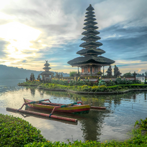 A canoe on a lake in Bali, Indonesia with a Hindu temple on the shore.