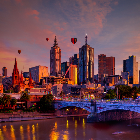 The Melbourne, Australia skyline at sunrise with hot air balloons in flight.