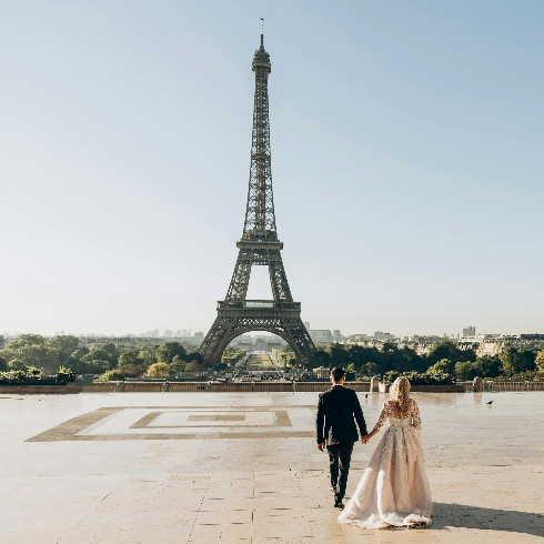 A bride and groom walking toward the Eiffel Tower in Paris, France.