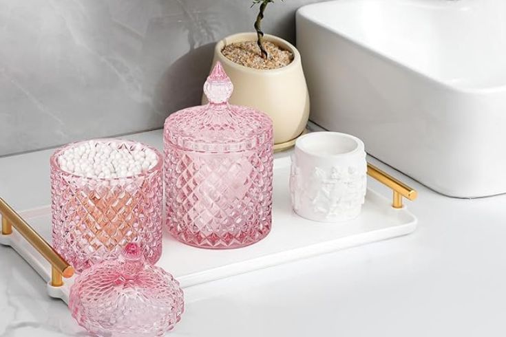 Pink apothecary jars on white tray in bathroom