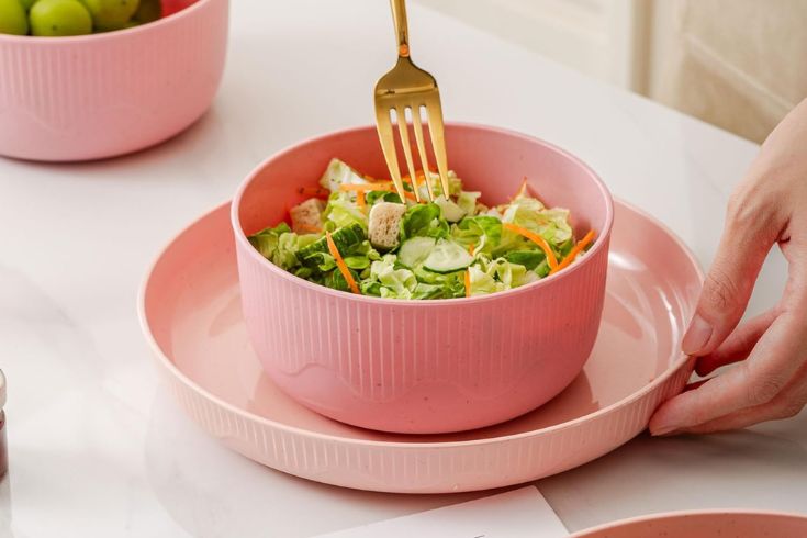 Salad inside pink bowl on top of pink plate