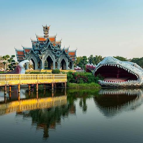 Ancient city in Bangkok Thailand, with a temple and large dragon sculpture in the water as part of HOME Network's 10 Unexpected Sunny Destinations For Your Winter Escape