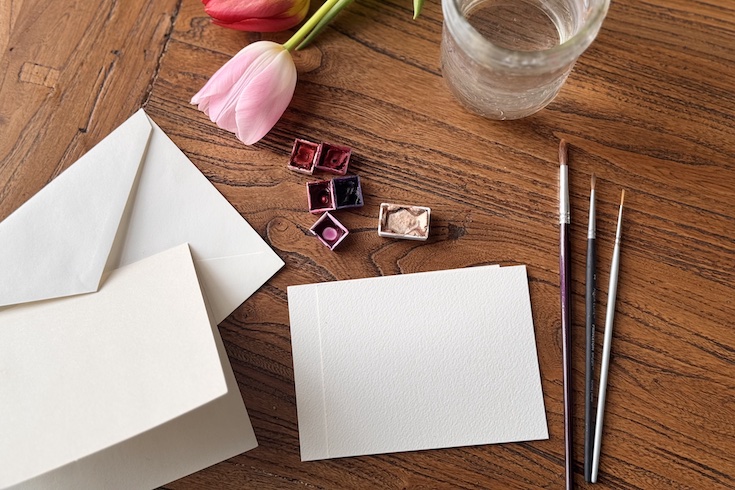 blank card shown on the table with brushes and watercolour paint colours