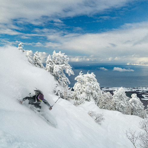 A single skiier speeding down a mountain at Niseko United Ski Resort in Hokkaido, Japan.