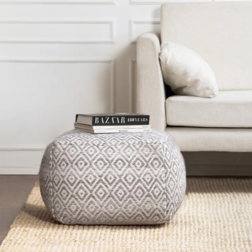 Gray upholstered pouf on a carpet.