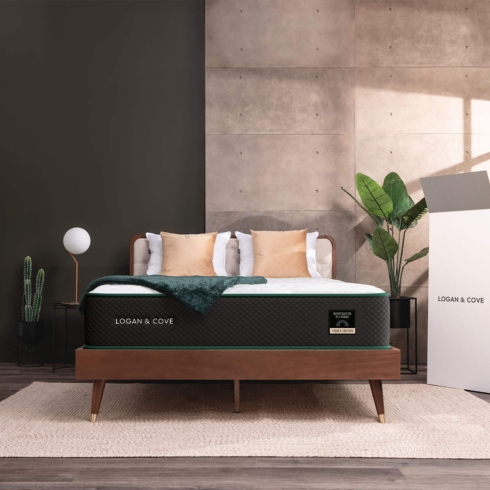 A Logan & Cove mattress featured on a wooden bed frame with pillows in a bedroom.