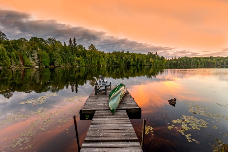 Green Canoe and Chairs on a Dock Next to a Lake at Sunset - Haliburton Highlands.